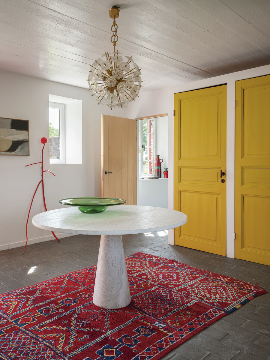 The entrance's canary yellow doors reveal a love of colour.  The red sculpture is an old handicraft of one of the girls.  Isabelle combined it with a rug and lamp from the thrift store and a table she bought at the Kloosterstraat in Antwerp, Mr. Frank.