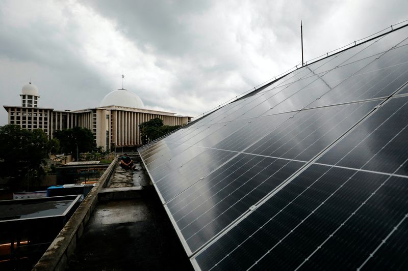 FILE PHOTO: A technician sits on the roof of a building that is installed with solar panels, at the Jakarta Catedral in Jakarta