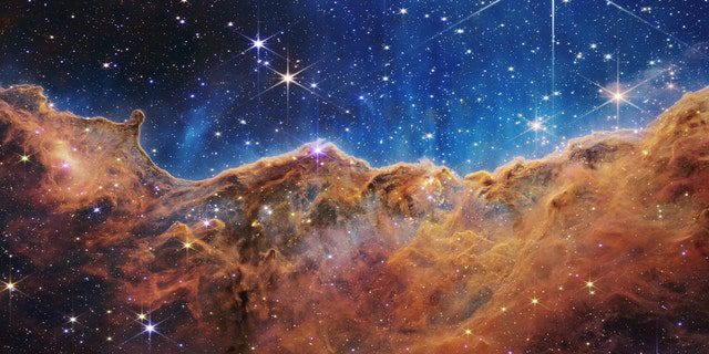What looks like rocky mountains on a moonlit night is actually the edge of the nearby young star-forming region NGC 3324 in the Carina Nebula.  This image, taken in infrared light by the Near Infrared Camera (NIRCam) on NASA's James Webb Space Telescope, reveals previously obscured regions of star birth.